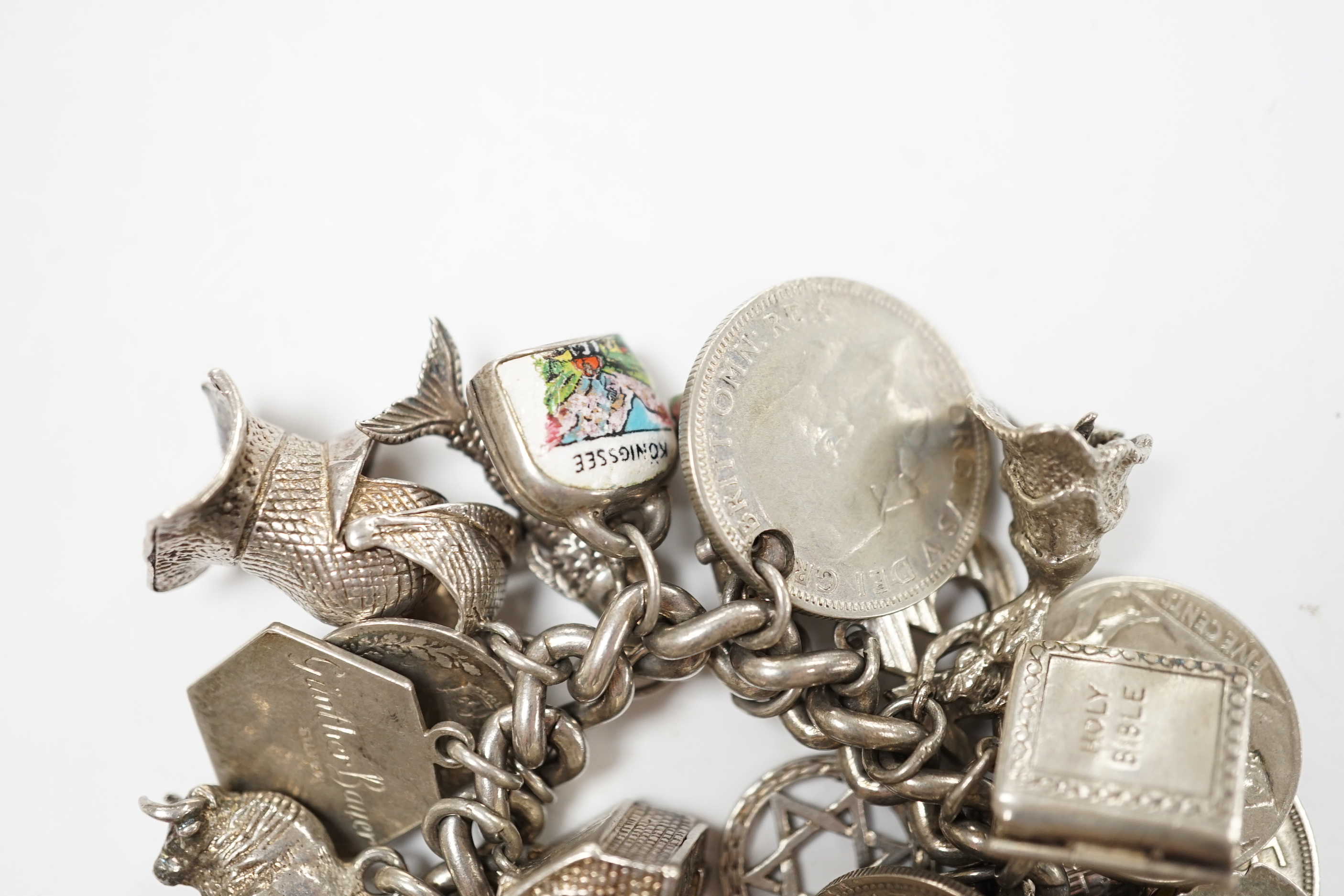 A silver charm bracelet, hung with assorted mainly white metal charms including tankard and Knight's helmet, two 'melted' ingots and a silver medallion.